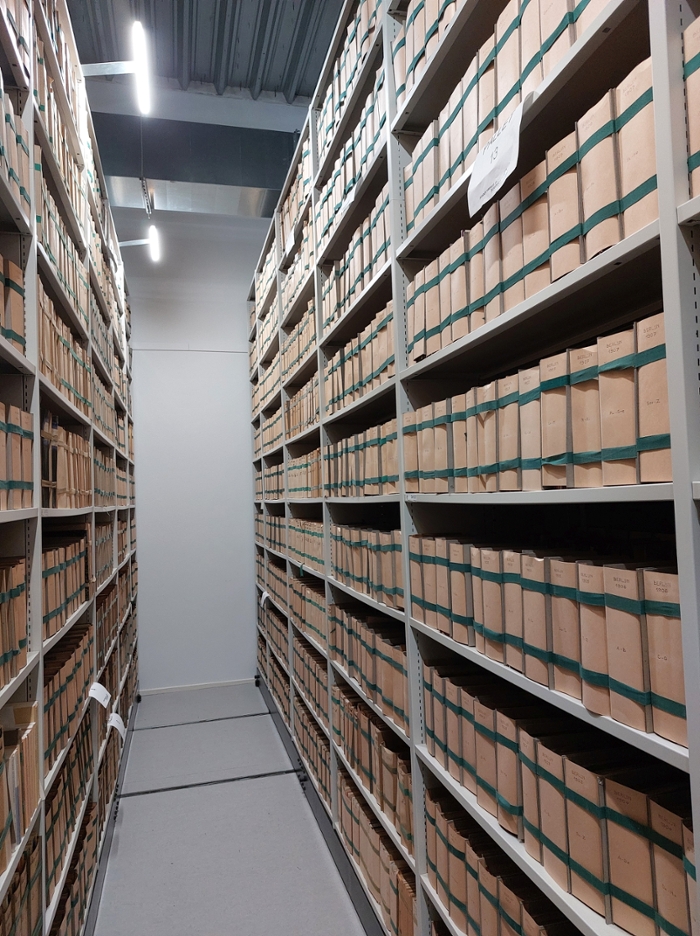 Aisles of shelves holding thousands of paper-wrapped, banded bundles of printed theses at Leiden